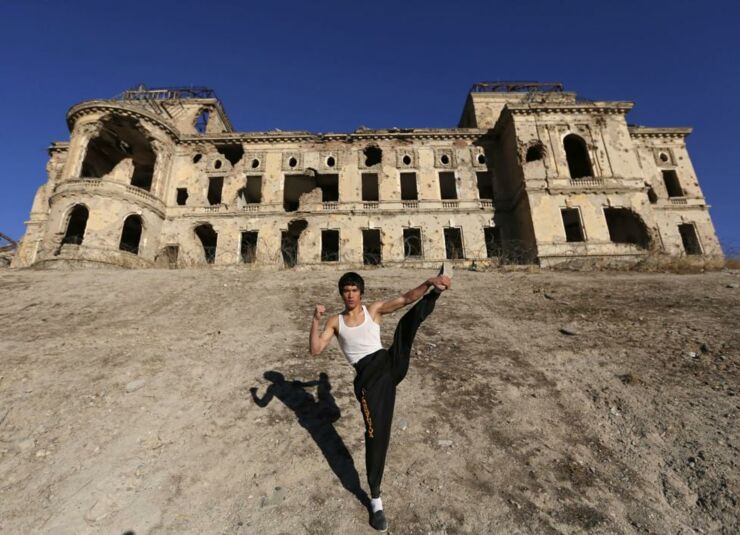 Abbas Alizada, who calls himself the Afghan Bruce Lee, poses for the media in front of the destroyed Darul Aman Palace in Kabul.